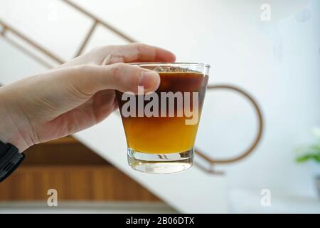Hand, die eine Tasse Orangensaft und Espresso-Kaffee in Eis hält Stockfoto