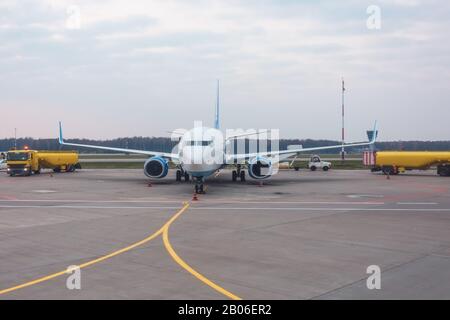 Trucks betanken mit Anhängern neben einem Passagierflugzeug Stockfoto