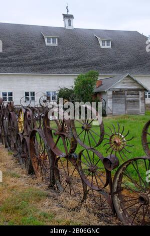 USA, STAAT WASHINGTON, PALOUSE COUNTRY IN DER NÄHE VON PULLMAN, UNIONTOWN, KUNSTSCHEUNE, ZAUN AUS ALTEN METALL-WAGENRÄDERN Stockfoto