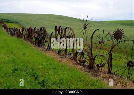 USA, STAAT WASHINGTON, PALOUSE COUNTRY IN DER NÄHE VON PULLMAN, UNIONTOWN, KUNSTSCHEUNE, ZAUN AUS ALTEN METALL-WAGENRÄDERN Stockfoto