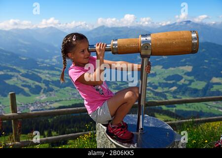 Mädchen, das durch ein Holzteleskop blickt, Gipfelpanorama der hohen Salve, Hopfgarten, Brixental, Kitzbüheler Alpen, Tyrol, Österreich Stockfoto