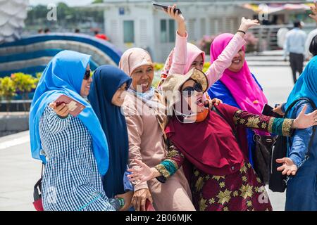 Mehrere Generationen muslimischer Frauen, die in Singapur gemeinsam einen Entführer für ein Gruppenbild tragen. Stockfoto