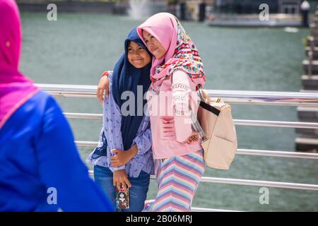 Indonesische Teenager tragen einen rosa und marineblauen Hijab-Schleier, die zusammen für ein Gruppenfoto posieren, gute Freundschaft. Merlion Park. Singapur. Stockfoto