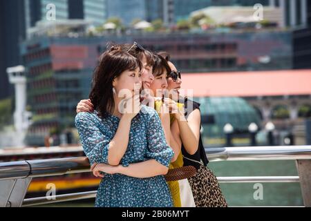 Vier hübsche junge japanische Touristen-Frauen posieren eng zusammen für ein unvergessliches Bild in Singapur. Südostasien. Stockfoto