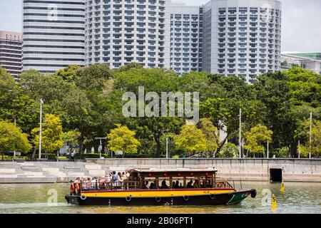 Besucher auf einem Bummelboot machen Fotos von der schönen Szene in Singapur. Stockfoto