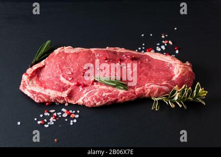 Lebensmittelkonzept Bio Glas füttern rohes Fleischfilet Rindersteak auf schwarzem Schiefersteingrund Stockfoto