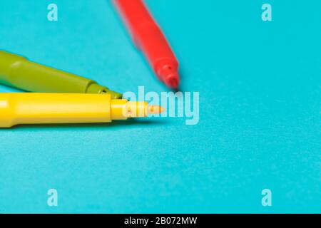 Mehrere farbige Filzstifte auf hellblauem Papierhintergrund werden nah beieinander gebracht Stockfoto
