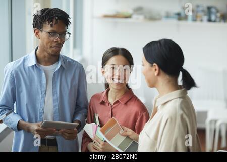 Erfolgreiche junge Designer stehen und diskutieren farbige Palette im Büro Stockfoto