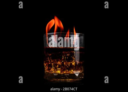 Glas mit Whiskey aus Eiswürfel und Feuerflamme auf schwarzem Hintergrund Stockfoto