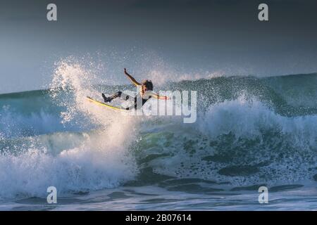 Spektakuläre Action, während ein junger Surfer eine große wilde Welle in Fistral in Newquay in Cornwall reitet. Stockfoto