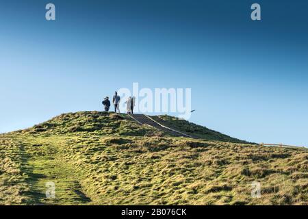 Menschen, die auf dem Gipfel der Überreste einer Frühbronzezeitlichen Barrow auf Porth Island Trevelgue Head in Newquay in Cornwall stehen. Stockfoto