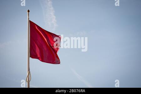 Flagge der Küstenwache; rot für Gefahr. Eine Markierung, die darauf hinweist, dass es unsicher ist, das Wasser zu betreten; gesetzt gegen blauen Himmel Kopierraum. Stockfoto