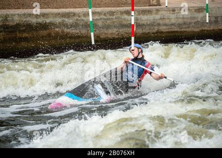 GB Canoe Slalom-Athlete in der C1W-Klasse der Frauen, die sich ausdehnt, um an der Stange eines Slalom-Tores auf weißem Wasser zu sein Stockfoto