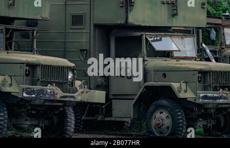 Vorderansicht des alten, zerstörten, militärisch grünen Lastwagens ist alter Flachreifen. Verlassene verrostende Militärlastwagen. Verfallener verlassener LKW mit Text der US-Armee auf der Motorhaube. Stockfoto