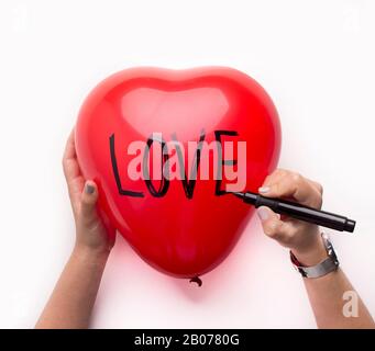 Frau bereitet sich vor, einen großen roten Herzballon zum valentinstag zu präsentieren Stockfoto