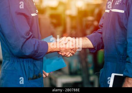 Das Mitarbeiterteam arbeitet mit dem Schütteln an der Zusammenarbeit mit dem Werksingenieur oder der Bearbeitung der erledigten Arbeit. Stockfoto