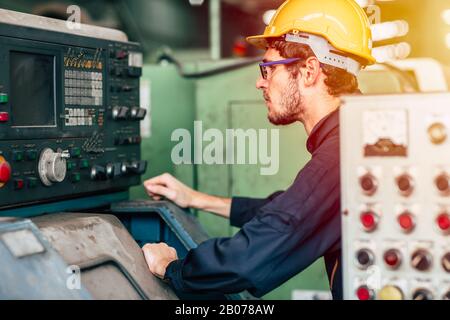 Techniker des jungen Berufs betreiben schwere Maschinen bis hin zur automatisierten CNC-Steuerung im Werk. Stockfoto