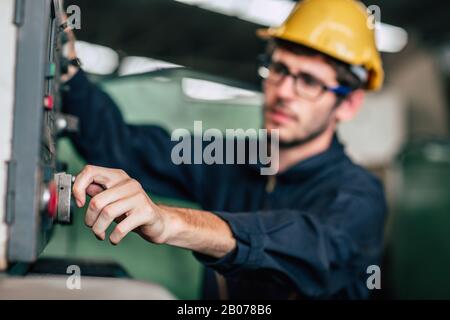 Ingenieur für junge Berufstechniker betreibt schwere Maschinen zur automatisierten CNC-Steuerung in der Hand der Naharbeiter. Stockfoto