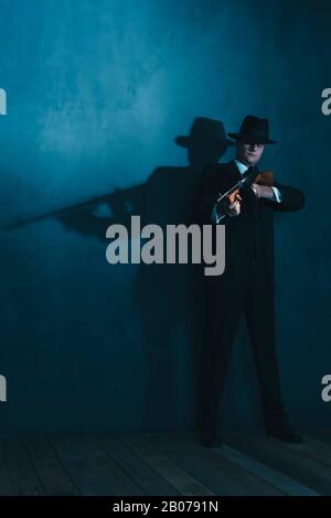 Retro-Gangster in Hutschüssen mit Maschinengewehr. Stockfoto