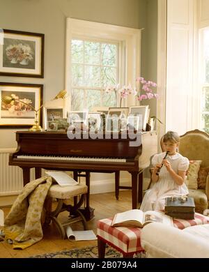 Kleine Mädchen, die Blockflöte vor PianoEDITORIAL SPIELEN, VERWENDEN NUR Stockfoto