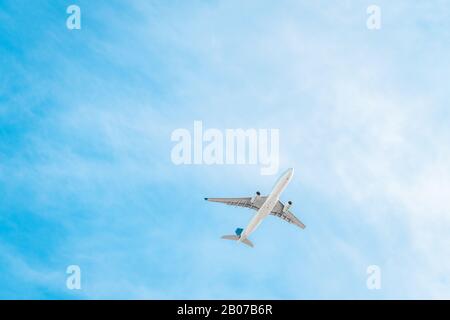 Großes kommerzielles Passagierflugzeug unter blauem Himmel von unten gesehen Stockfoto