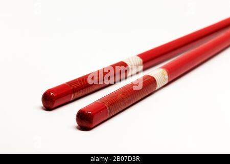 Zwei rote japanische Essstäbchen in Holz auf weißem Hintergrund Stockfoto