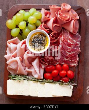 Kleine Holz-Chartuterie und Käseplatine mit Trauben und Kirschtomaten Stockfoto