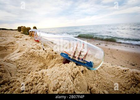 Flasche mit Schiff im Inneren am Strand liegend. Stockfoto