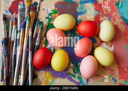 Nahaufnahme farbiger Ostereier auf dem Gemälde mit Pinseln bereit zum Osterfeiertag Stockfoto