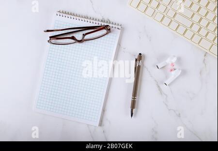 Tischgeräte mit Notebook-Tastatur kabellose Kopfhörer Brille Stift Stockfoto