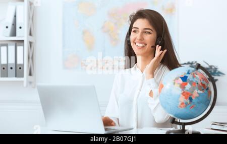 Reisebüro. Frau berät Kunden und trägt Headset Stockfoto