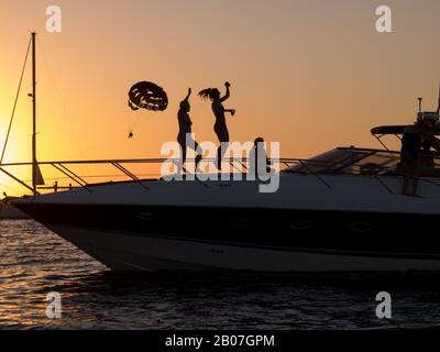 Partygäste auf Ibiza tanzen bei Sonnenuntergang auf einem Boot, das vor der Küste vom Cafe Mambo in der Partyhauptstadt San Antonio auf der Partyinsel Ibiza vor Anker liegt Stockfoto