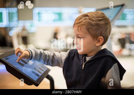 Der Junge entscheidet sich für den Einkauf auf dem Bildschirm in einem modernen Geschäft Stockfoto