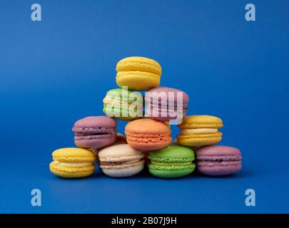 Bunte runde, gebackene Makaronkuchen auf dunkelblauem Grund, Dessert steht in einer Reihe Stockfoto