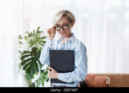 Ordner "Counsel Lady Holding" Lächelt An "Camera Standing In Office" Stockfoto