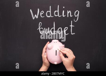 Überreichen Sie das Sammeln von Münzen in die Schweinebank über die Tafel Stockfoto