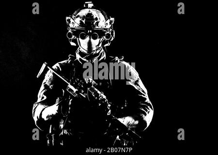 Armee-Elitesoldat mit versteckt hinter Maske und Brille Gesicht, in voller taktischer Munition, ausgerüstetem Nachtsichtgerät, Funk-Headset, bewaffnetem Kurzfass Dienstgewehr Studio Kontur Schuss Stockfoto