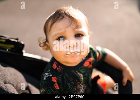 Mutter füttert Baby Kind Junge Eiscreme - Junge Mutter und ihr Baby essen weißes Vanille cremig Dessert - Sitzt in einem Babywagen Kinderwagen - kaukasische Familie 1 Stockfoto