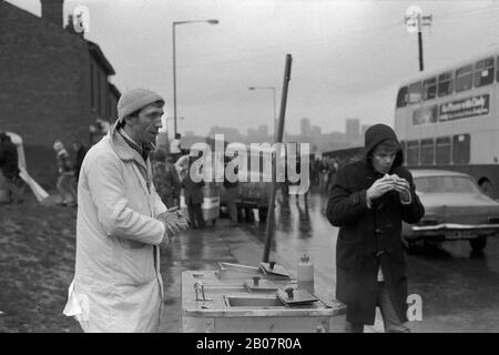 Schlechtes Wetter nach Hause, Fastfood-Verkäufer und junger Mann im Duffelmantel essen einen Snack. Das Fußballspiel von Coventry City wird im Highfield Road Stadium beendet. Um die 1981 1980er Jahre in Großbritannien. HOMER SYKES Stockfoto