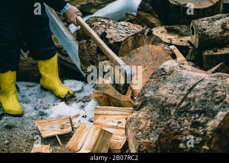 Mann hackt Holz mit Vintage-Axt. Details zu fliegenden Holzstücken auf Holzklotz mit Sägemehl. Stockfoto