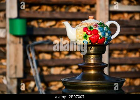 Nahaufnahme der Teekanne, die auf einem Samovar steht. Traditionen des russischen Teetrinkens. Brennholz. Stockfoto