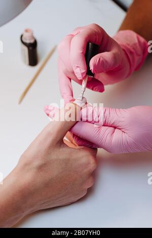 Nahaufnahme eines Mädchens in rosafarbenen Handschuhen macht Maniküre Stockfoto