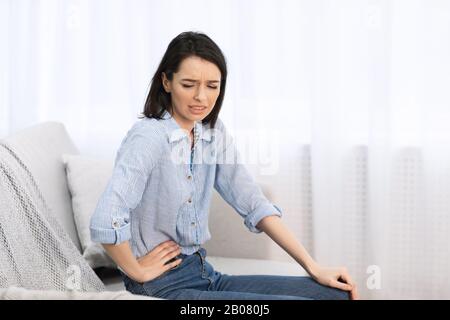 Junge Frau, die an Schmerzen leidet Stockfoto