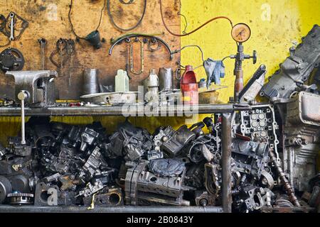 Nahaufnahme einer Reihe von gebrauchten rostigen und öligen Motorteilen und verschiedenen Werkzeugen in einer Auto-Junk- und Reparaturwerkstatt in Iloilo City, Philippinen, Asien Stockfoto