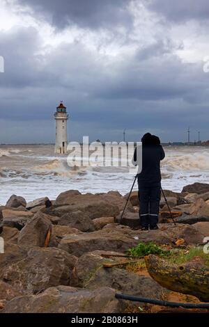 Fotograf mit einer Kamera auf einem Stativ, der während Storm Ciara ein Foto von Fort Perch Lighthouse in New Brighton Wallasey machte Stockfoto