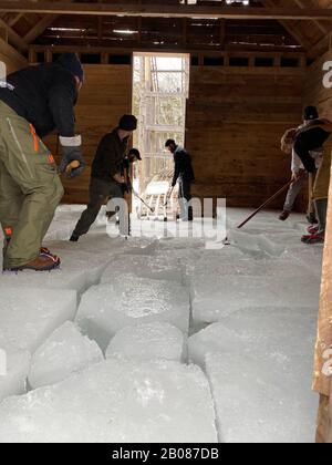 Dieses Foto stammt vom 16. Februar 2020 und wurde in South Bristol, Maine, auf dem Ice Harvest Festival in Thompson Pond aufgenommen. Freiwillige sammeln sich, um Eis aus dem Teich zu schneiden, wie sie es in den 1820er Jahren an diesem Standort hatten. Das Gelände wurde in den 1980er Jahren geschlossen. Heute verwenden sie dieselben Geräte, die in der Vergangenheit verwendet wurden. Das Eis war in erster Linie für den lokalen Verbrauch bestimmt. Jetzt werden die Eisblöcke aufbewahrt und verwendet, um Eis für die jährliche Eiscreme Social im Sommer zu machen. Stockfoto