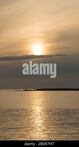 Emotionaler Schuss einer Bucht bei Sonnenaufgang oder Sonnenuntergang bei Hintergrundbeleuchtung mit sehr bewölktem Himmel Stockfoto