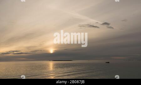 Emotionaler Schuss einer Bucht bei Sonnenaufgang oder Sonnenuntergang bei Hintergrundbeleuchtung mit sehr bewölktem Himmel Stockfoto