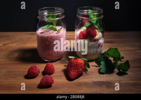 Erdbeer-Smoothie auf einer Holzplatte mit schwarzem Hintergrund, Werbefläche Stockfoto