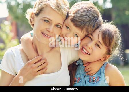 Porträt einer glücklichen Familie im Freien. Mama mit Kindern im Sommer. Mutter und Kinder. Stockfoto